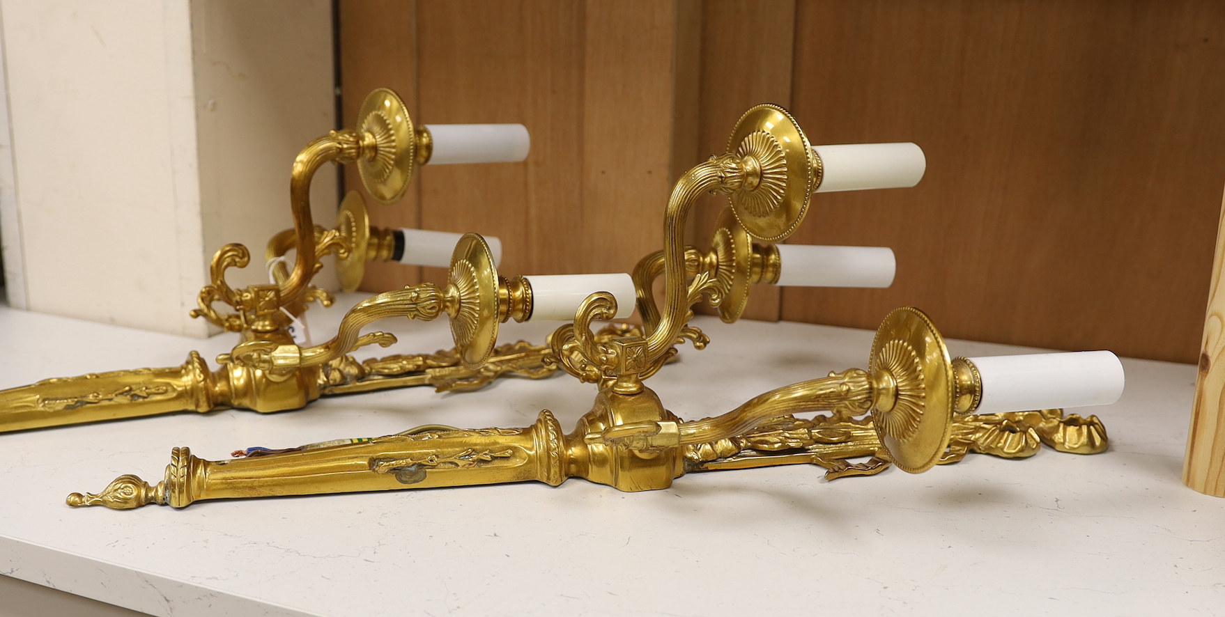 A pair of gilt metal three branch wall lights, 61cm tall